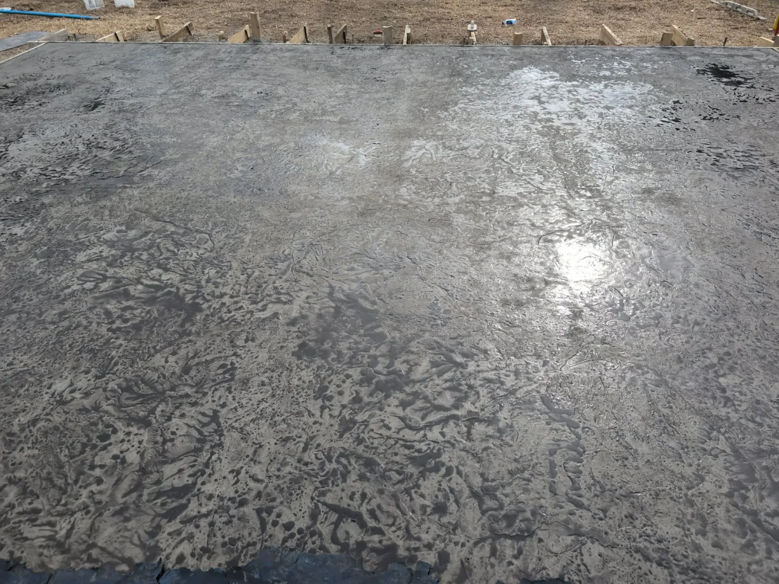 Stamped concrete foundation with decorative texture and patterning, wooden posts visible