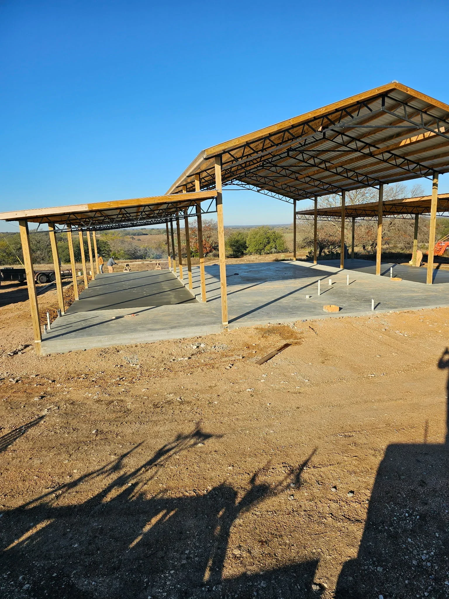 Concrete slab foundation with steel pavilion frame, control joints visible on finished pad