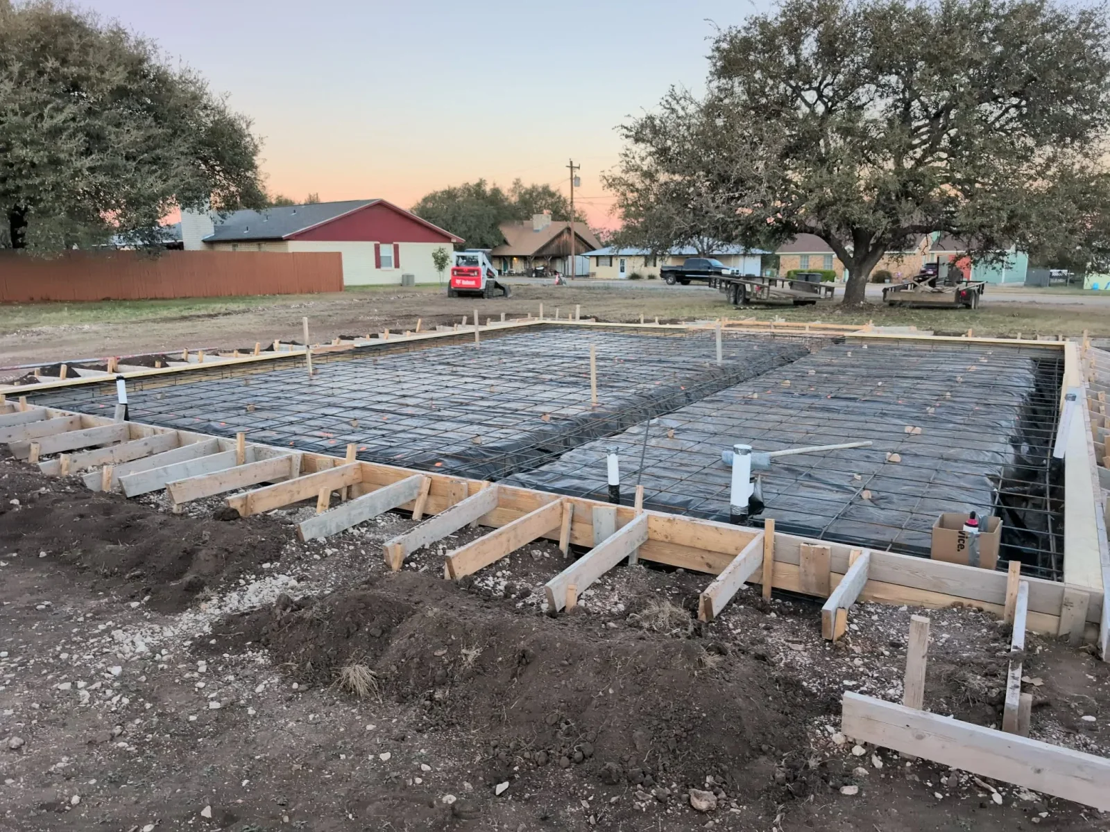 Concrete foundation with rebar grid, wooden forms, and prepared subgrade for residential construction