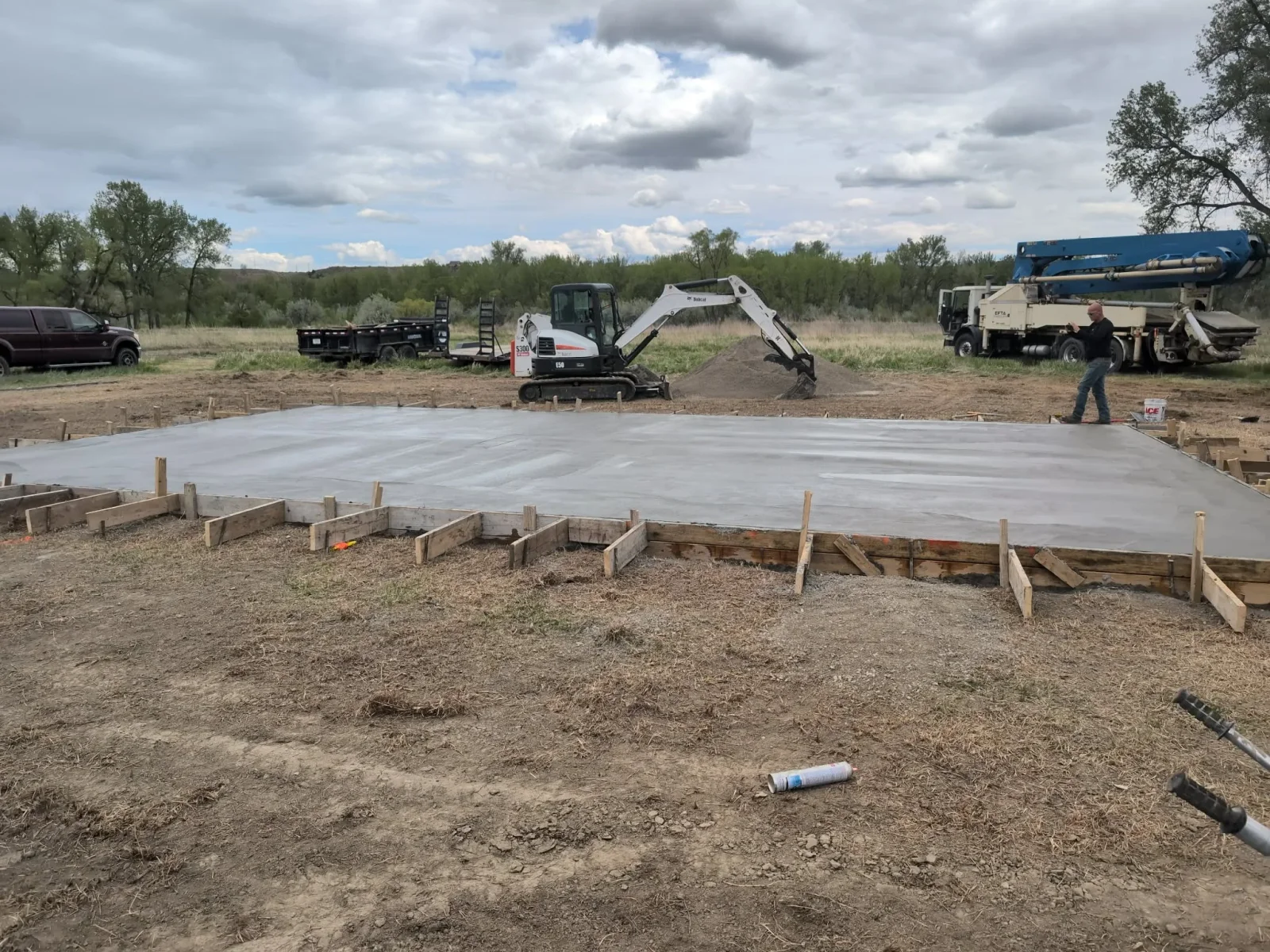 Freshly poured concrete foundation slab with wooden forms and stakes on prepared ground
