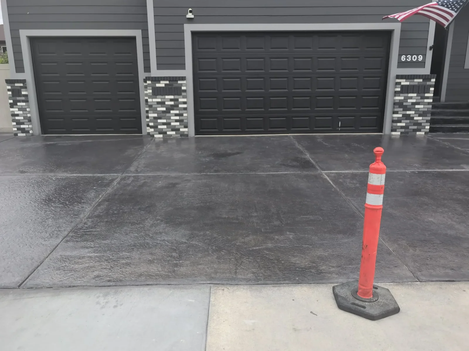 Dark gray decorative concrete driveway with scored panel lines and three-car garage apron