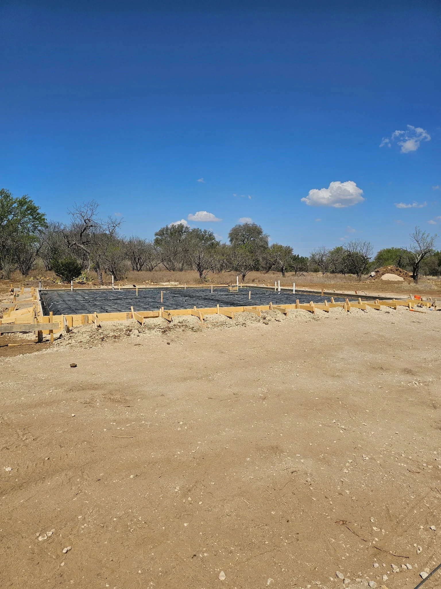 Wooden frame with black moisture barrier on prepared earth base for concrete foundation