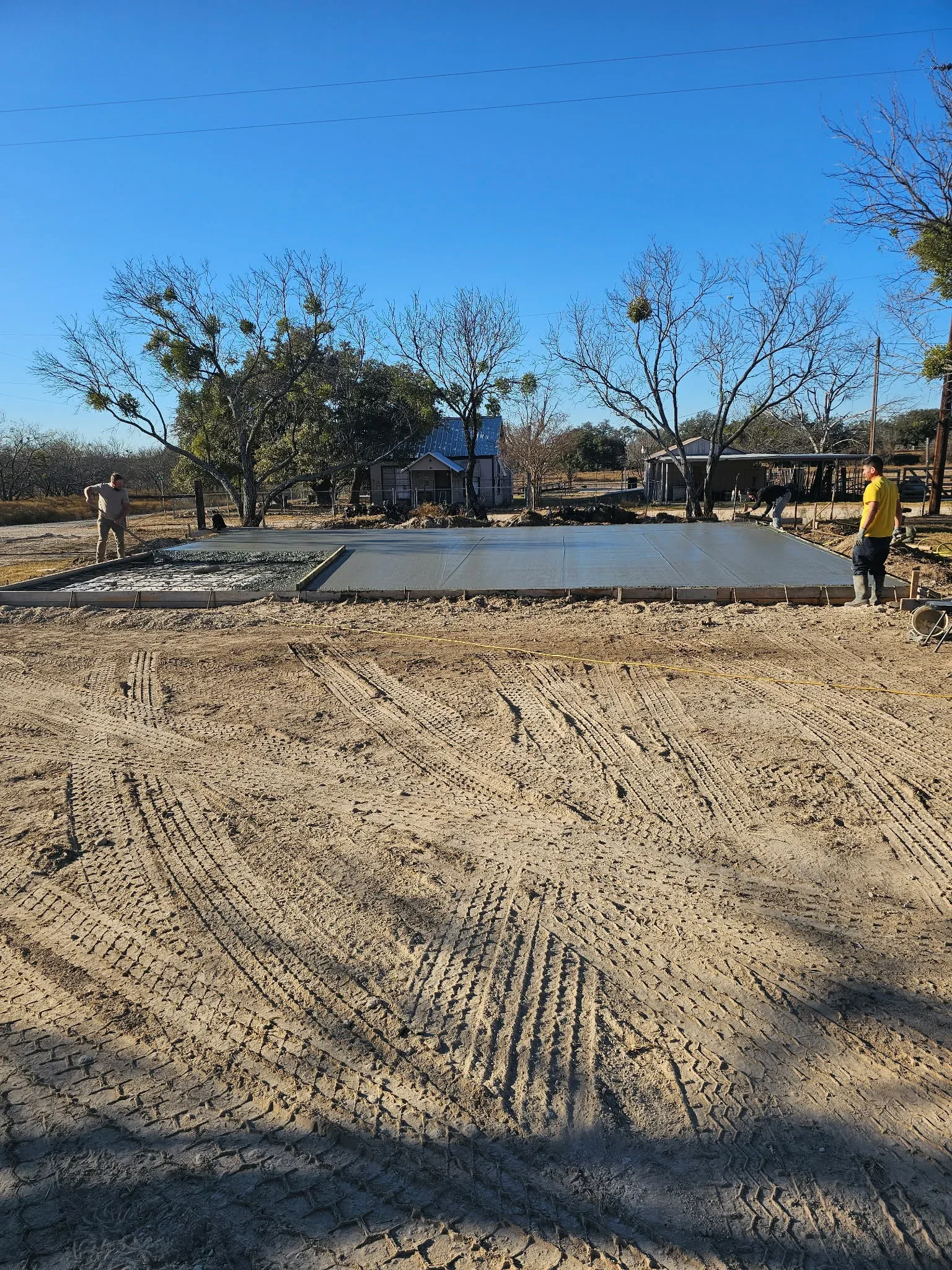 Finished concrete pad with smooth trowel surface on prepared soil base, residential setting