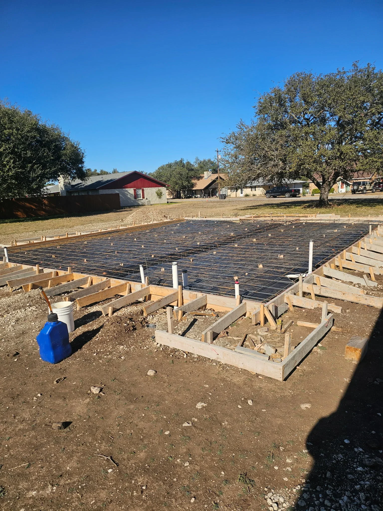 Concrete slab foundation with rebar grid, wooden forms, and concrete footings on rural property