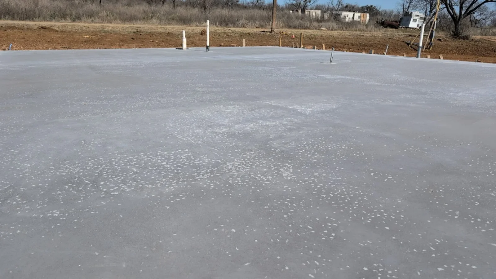 Finished concrete foundation slab with white perimeter posts and proper grading